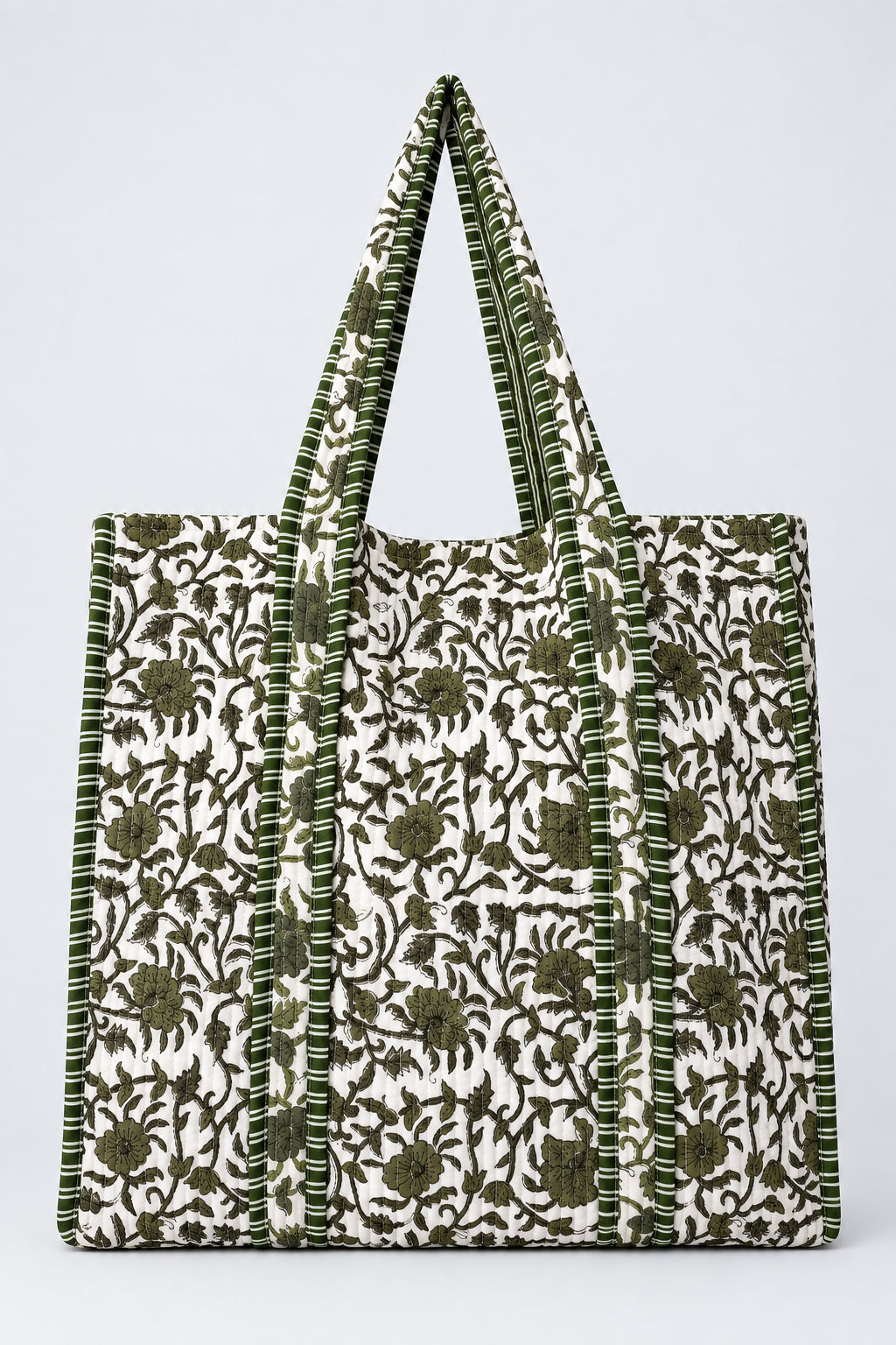A large tote bag with a white and olive green floral block print pattern, hanging from a clear plastic display hook against a plain light gray wall.