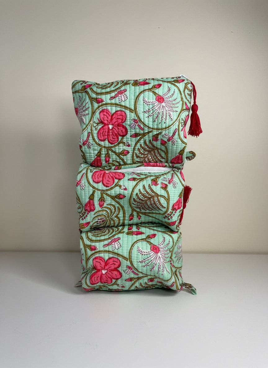 Stack of floral fabric bags with tassels on a plain background