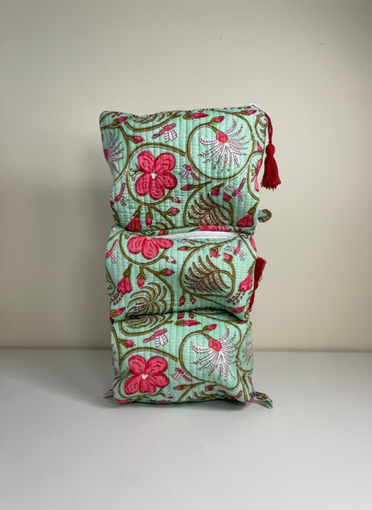 Stack of floral fabric bags with tassels on a plain background
